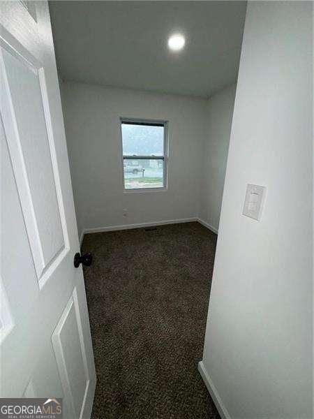 spare room featuring dark carpet