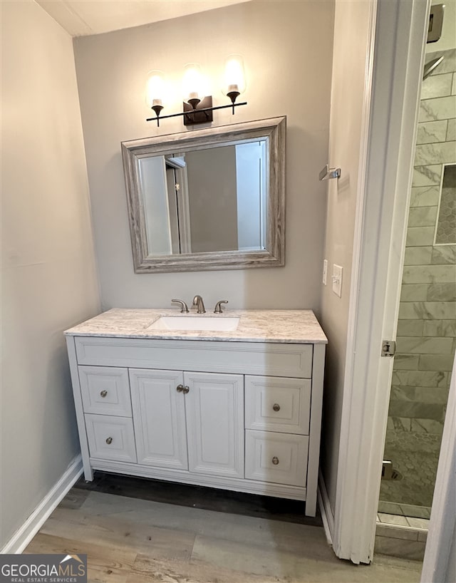 bathroom with a tile shower, hardwood / wood-style floors, and vanity