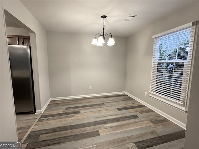 unfurnished dining area featuring a chandelier and dark hardwood / wood-style floors