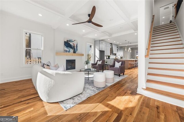 living room with hardwood / wood-style floors, ceiling fan, beamed ceiling, and coffered ceiling