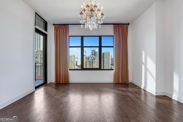 unfurnished room with a notable chandelier and dark wood-type flooring