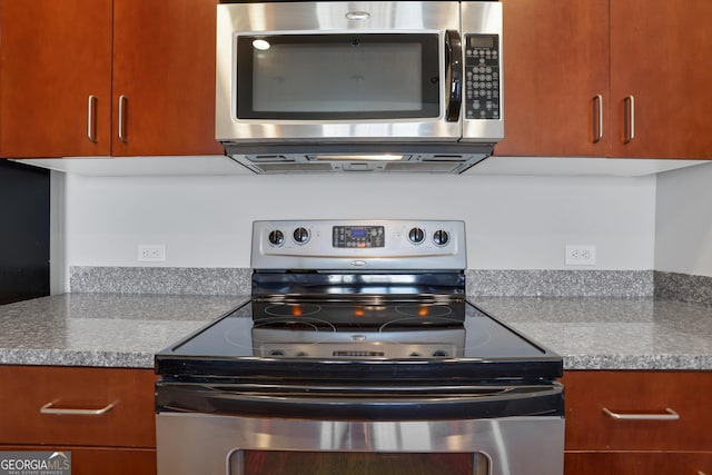 kitchen with appliances with stainless steel finishes, light stone counters, and range hood