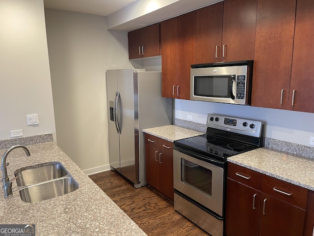 kitchen with light stone counters, sink, dark wood-type flooring, and appliances with stainless steel finishes