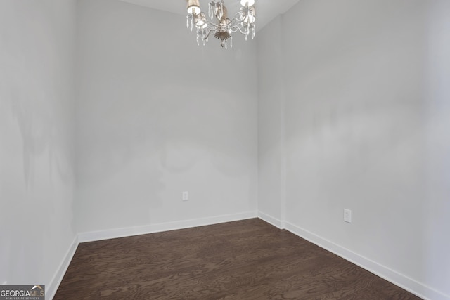 empty room with dark hardwood / wood-style floors and a chandelier