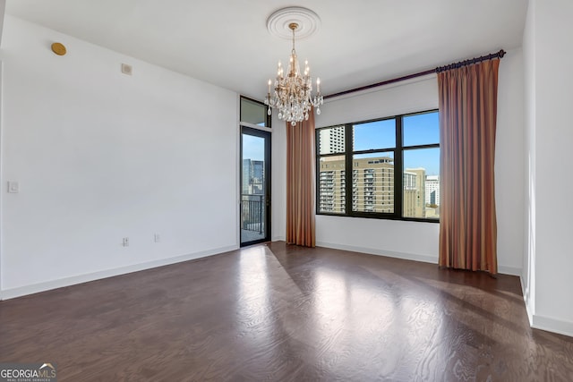 spare room with dark hardwood / wood-style flooring and a chandelier