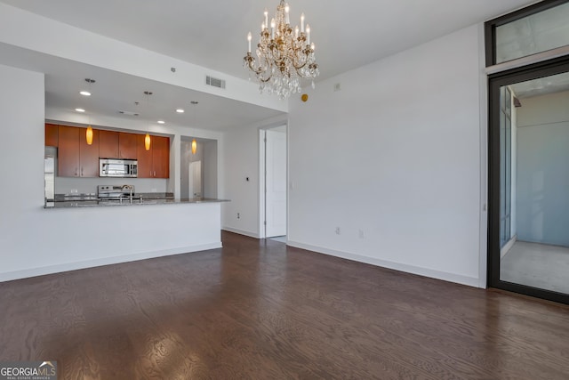 unfurnished living room with sink, dark wood-type flooring, and a chandelier