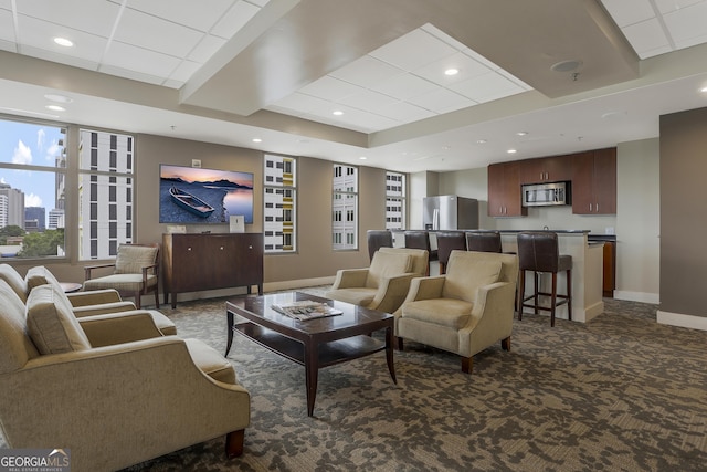 living room featuring a paneled ceiling, a tray ceiling, and dark carpet