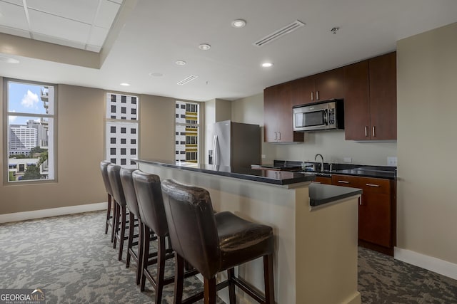 kitchen with sink, appliances with stainless steel finishes, dark brown cabinets, a kitchen breakfast bar, and a center island