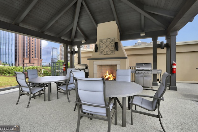 view of patio featuring a gazebo, area for grilling, and exterior fireplace