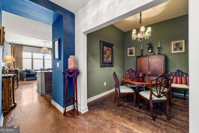 dining space featuring dark wood-type flooring and an inviting chandelier