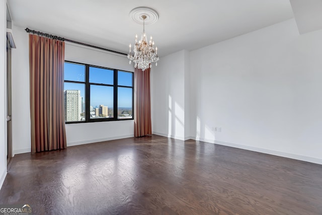 empty room with dark wood-type flooring and a chandelier