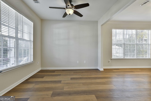 unfurnished room with ornamental molding, dark hardwood / wood-style floors, ceiling fan, and a healthy amount of sunlight