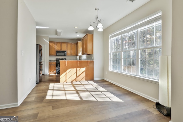 kitchen with kitchen peninsula, light hardwood / wood-style flooring, plenty of natural light, and black appliances