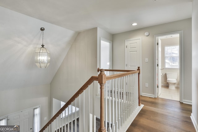 hallway featuring a chandelier, dark wood-type flooring, and vaulted ceiling