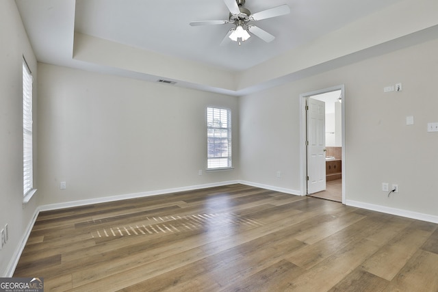 spare room with hardwood / wood-style flooring, a raised ceiling, and ceiling fan