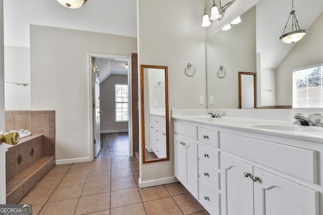 bathroom with tile patterned floors, vanity, vaulted ceiling, and a bathtub