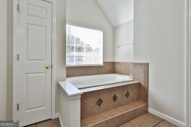 bathroom with tile patterned floors, tiled bath, and lofted ceiling