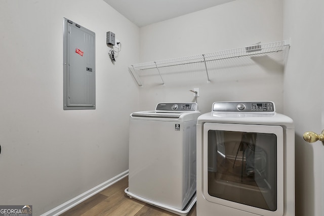 laundry room featuring washer and dryer, electric panel, and dark hardwood / wood-style floors