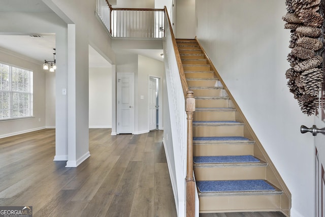 stairs featuring ornamental molding, a chandelier, and hardwood / wood-style flooring