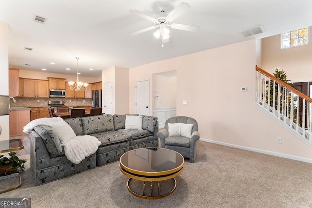 living room featuring sink, light colored carpet, and ceiling fan with notable chandelier