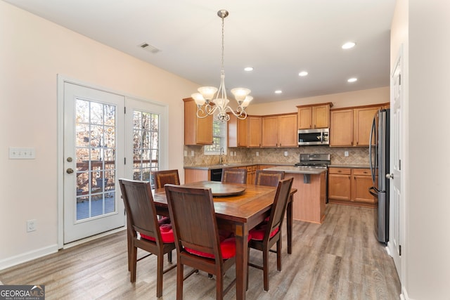 dining space with light hardwood / wood-style flooring, a chandelier, and sink