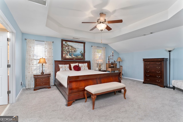 carpeted bedroom with a tray ceiling and ceiling fan