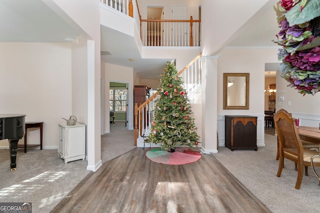 carpeted entryway with crown molding, a high ceiling, and an inviting chandelier