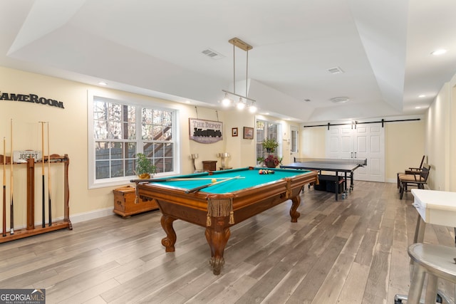 playroom with wood-type flooring, a barn door, a tray ceiling, and billiards