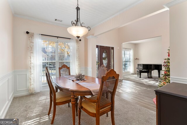 dining space featuring light hardwood / wood-style floors, crown molding, and a wealth of natural light