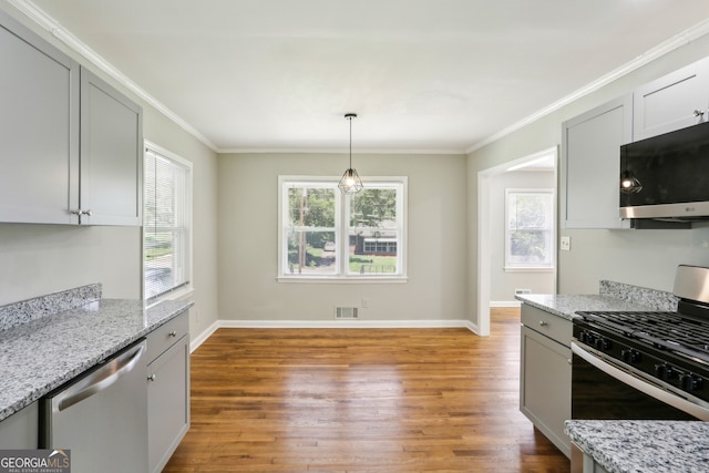 kitchen featuring appliances with stainless steel finishes, light stone counters, crown molding, pendant lighting, and light hardwood / wood-style flooring