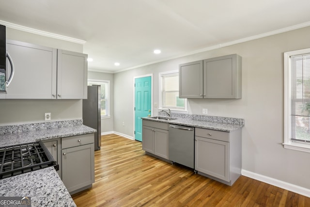 kitchen with gray cabinetry, a healthy amount of sunlight, light wood-type flooring, and appliances with stainless steel finishes