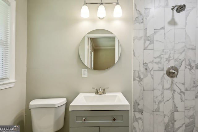 bathroom featuring a tile shower, vanity, and toilet