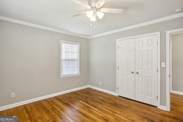 unfurnished bedroom with ceiling fan, wood-type flooring, ornamental molding, and a closet