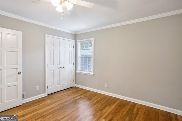 unfurnished bedroom with a closet, hardwood / wood-style flooring, ceiling fan, and ornamental molding