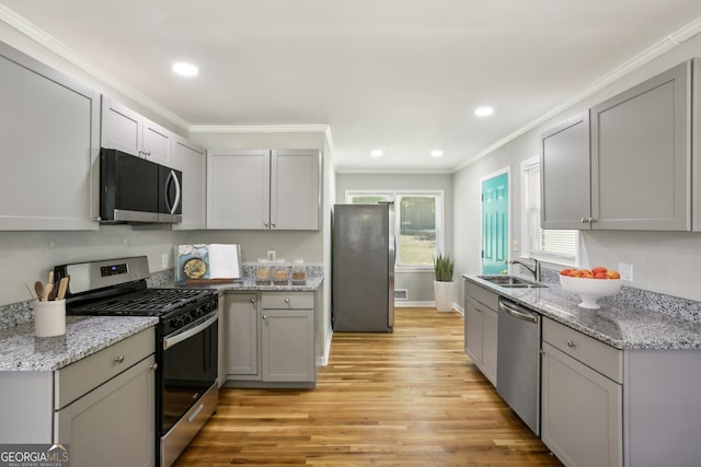 kitchen with gray cabinetry, sink, stainless steel appliances, light hardwood / wood-style floors, and ornamental molding