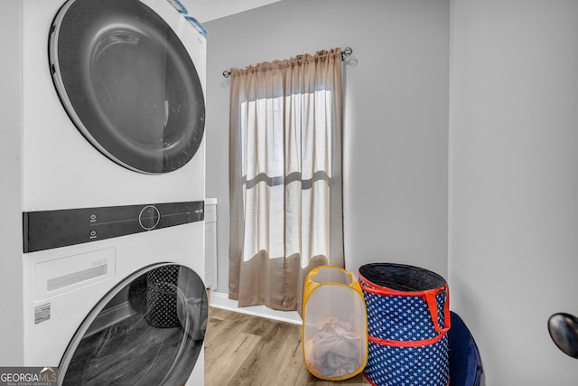 clothes washing area featuring a wealth of natural light, stacked washer and dryer, and light hardwood / wood-style floors