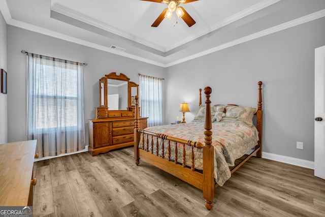 bedroom featuring a tray ceiling, ceiling fan, ornamental molding, and hardwood / wood-style flooring