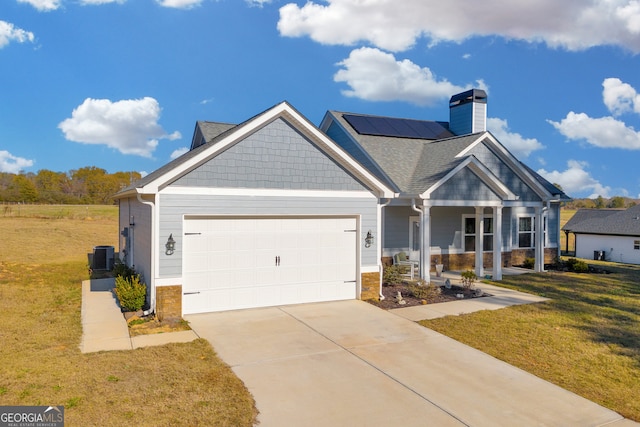 craftsman-style home with central air condition unit, a front lawn, a garage, and solar panels