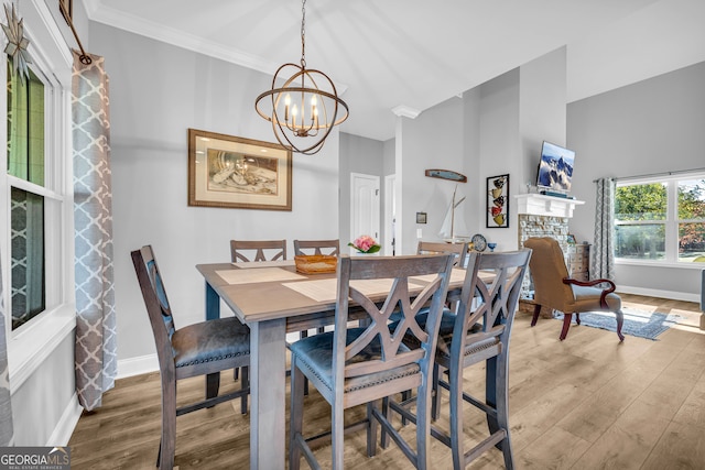 dining space with hardwood / wood-style flooring, ornamental molding, and an inviting chandelier