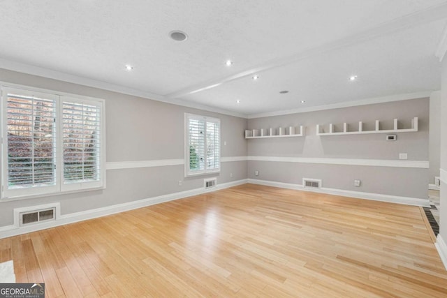 spare room with light hardwood / wood-style floors, a textured ceiling, and ornamental molding