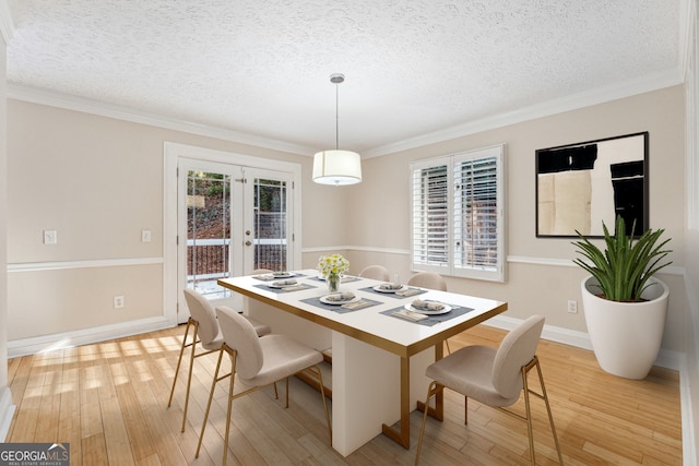 dining area featuring french doors, light hardwood / wood-style floors, a textured ceiling, and ornamental molding