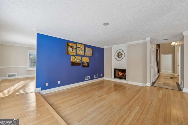 unfurnished living room featuring a large fireplace, light hardwood / wood-style floors, and a textured ceiling