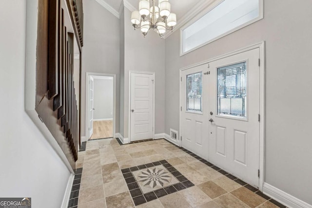 foyer entrance featuring a notable chandelier, a towering ceiling, and crown molding