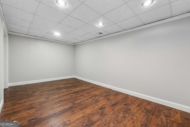 spare room with a drop ceiling and dark hardwood / wood-style floors