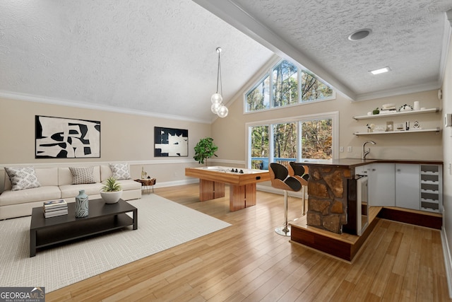 interior space with high vaulted ceiling, crown molding, light hardwood / wood-style flooring, a textured ceiling, and beverage cooler