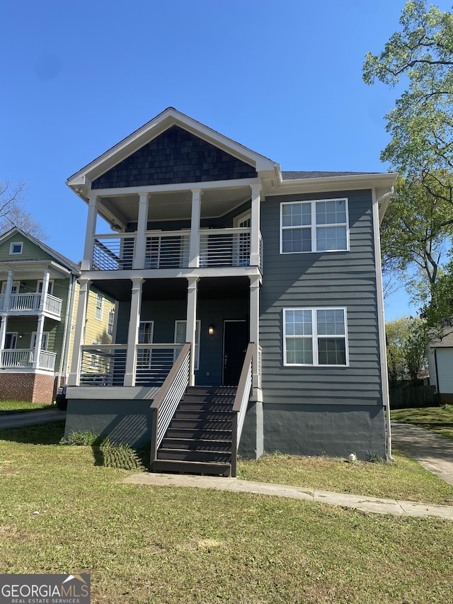 view of front facade featuring a balcony, covered porch, and a front yard