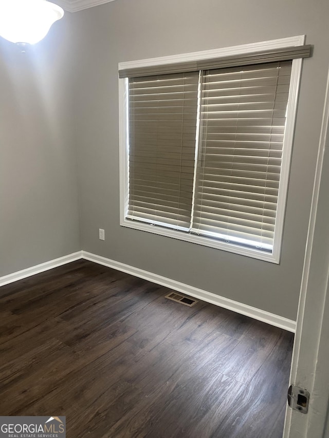 spare room with ornamental molding and dark wood-type flooring