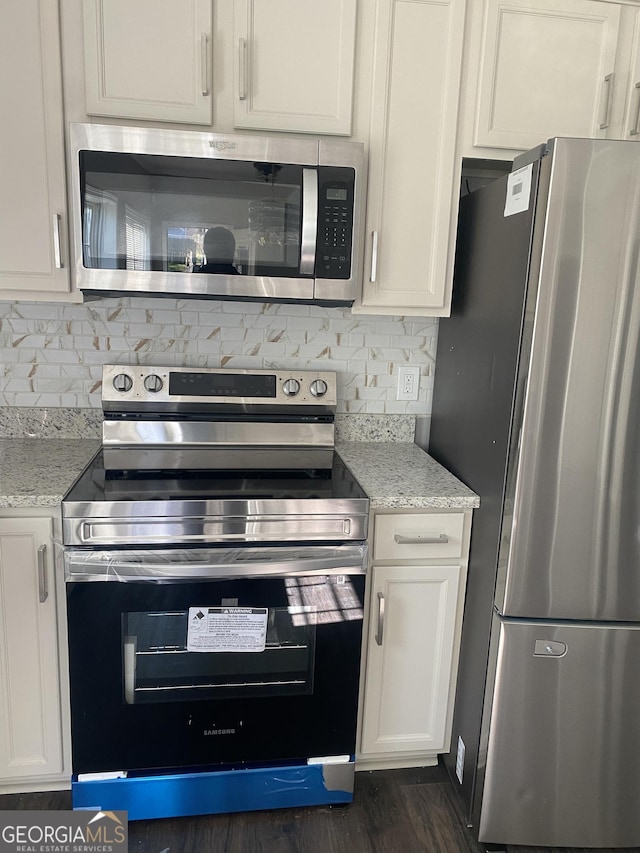 kitchen featuring white cabinets, light stone counters, and appliances with stainless steel finishes