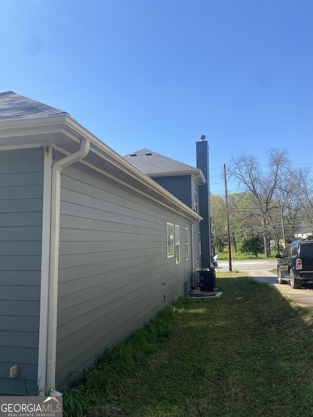 view of side of property with a lawn and central AC