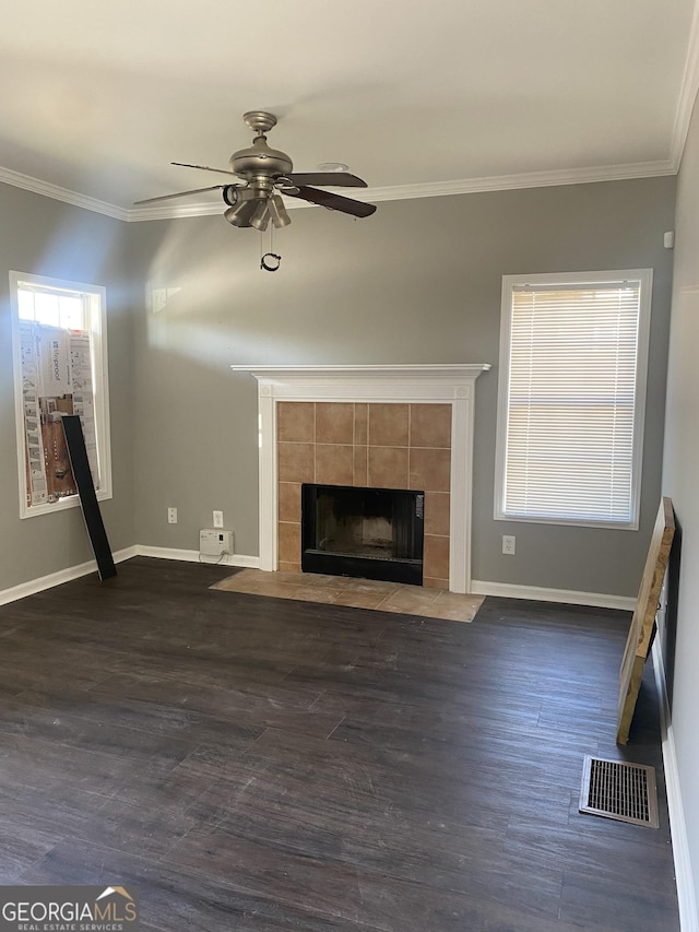 unfurnished living room with dark hardwood / wood-style flooring, ceiling fan, ornamental molding, and a tiled fireplace